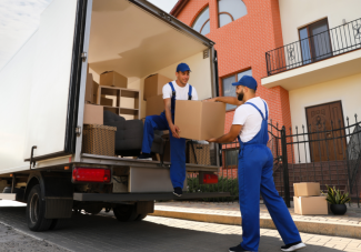 Two men wearing overalls taking boxes out of the back of a lorry